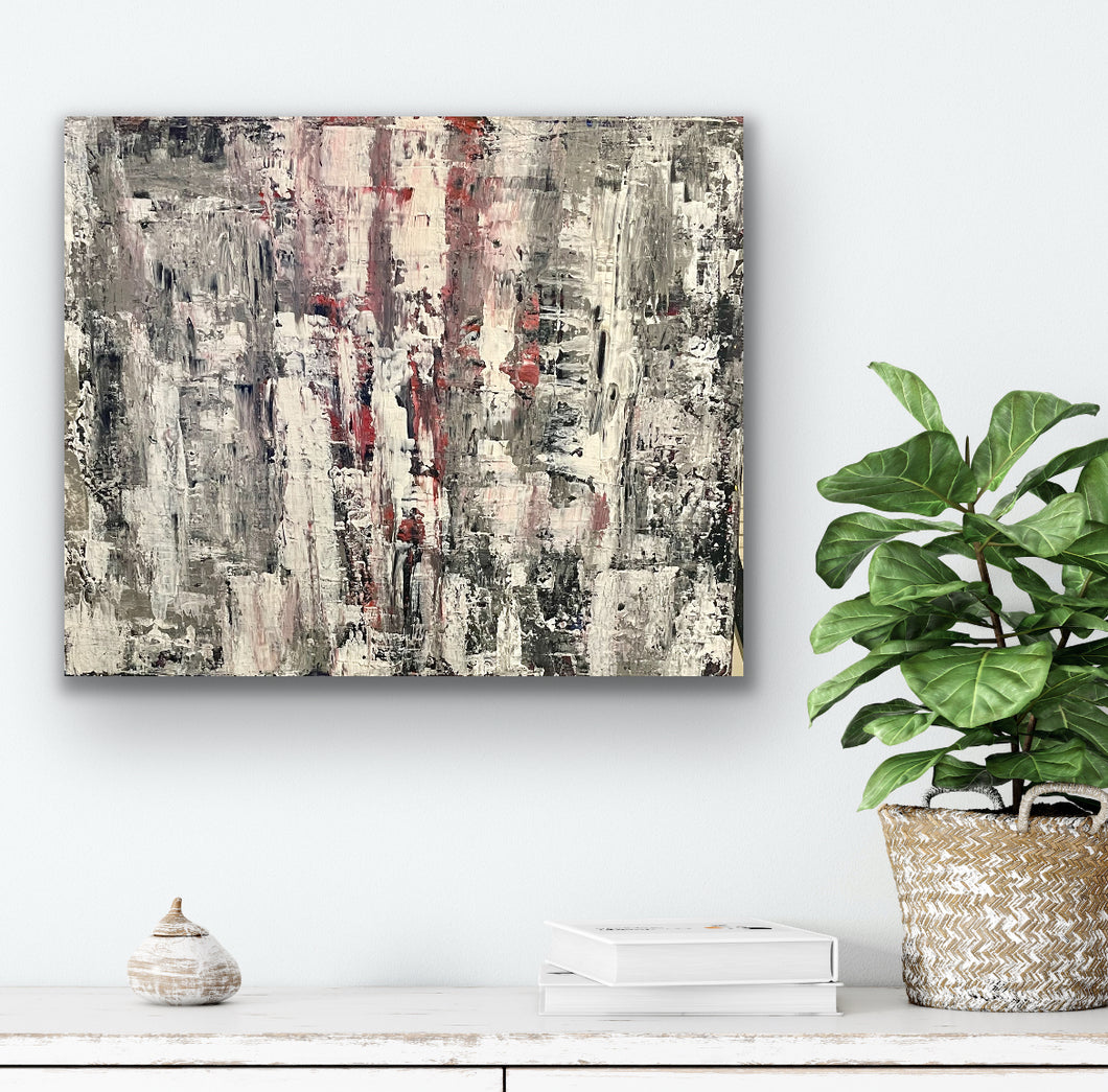 Abstract painting on a wall with a plant and decorative items below.