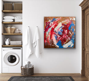 Abstract painting on a wall in a laundry room with shelves and washing machine.